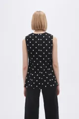 Chaleco largo sin mangas negro con estampado de lunares blancos, cuello en V y corte entallado.