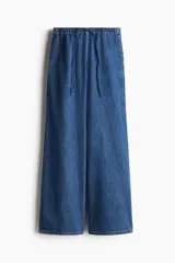 Pantalón de denim azul de corte holgado, con cintura elástica ajustable con cordón, bolsillos laterales y piernas anchas.