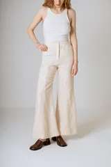 Pantalón de lino color beige, corte flare, tiro medio y costuras verticales al frente.
