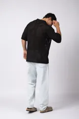 Camisa negra tejida de manga corta, con calado aireado, cuello tipo bowling y botones al tono. Diseño de corte relajado.