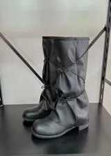 Botas bucaneras negras de cuero vegano, con caña alta arrugada y cordones cruzados ajustables.