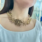 Collar dorado con diseño floral, elaborado con cuentas de diferentes tamaños y tonos de dorado.