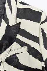 Blazer con estampado animal en blanco y negro, cuello solapa de muescas y manga larga acabada en abertura y botones. Bolsillos con solapa en delantero y de vivo en pecho. Cierre frontal cruzado con botones.