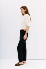 Pantalón negro de tiro alto con elástico interno en la cintura, botones falsos y terminación con volado. Tiene bolsillos aplicados en delantero y falsos en espalda.