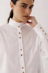 Camisa blanca de algodón con pespuntes cobrizos y detalle de volado en mangas y cuello.