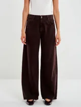 Pantalón de denim color marrón oscuro, tiro medio, con pierna ancha y recta. Presenta diseño clásico de cinco bolsillos y cierre con botón y cremallera.