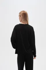 Buzo negro de punto canalé, corte holgado, cuello redondo y mangas largas.