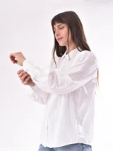 Camisa verde oliva con rayas verticales en relieve, corte clásico, cuello camisero, cierre frontal con botones blancos, mangas largas abullonadas con puños elastizados.
