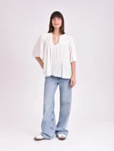 Blusa blanca de mangas cortas con escote en V y lazos.