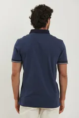 Chomba blanca de piqué con cuello y puños en azul marino.