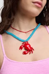 Collar con cuentas de color celeste y dije de cangrejo rojo.