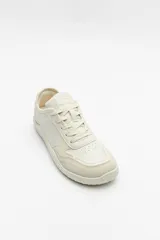 Zapatillas de cuero color blanco y beige, de diseño minimalista con suela marrón.
