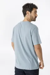 Remera celeste de manga corta con cuello redondo y estampado en el pecho con un diseño geométrico y la inscripción "Benson & Thomas Design Lab".