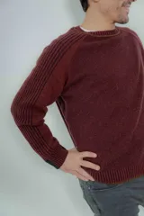 Sweater marrón de lana lambswool con cuello redondo y mangas largas. Presenta un diseño de punto texturizado en el cuerpo y mangas con detalle de punto acanalado en hombros y puños.