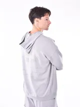 Buzo hoodie gris con bolsillo canguro y capucha con cordones ajustables. Diseño holgado con puños y cintura acanalados.