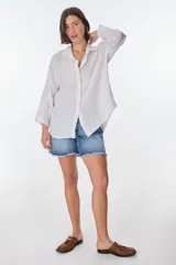 Camisa de lino color blanco, de manga larga y corte holgado, con cuello camisero y cierre frontal de botones.