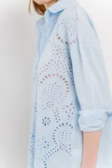 Camisa celeste de algodón con bordado calado tipo broderie, manga larga con puño angosto y botones al frente.