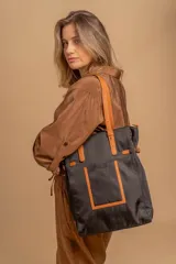 Cartera tipo tote bag color negro, con doble asa de mano y correa bandolera ajustable. Presenta un bolsillo rectangular en el frente.