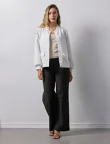 Campera bomber blanca con cuello a la base, abertura central con botones, bolsillos delanteros, ruedo y puños elastizados.