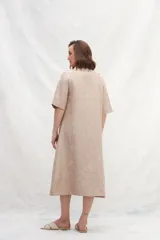 Vestido camisero midi color beige, de lino, con abotonadura frontal completa, manga ranglan, bolsillos laterales y un volante en el ruedo.