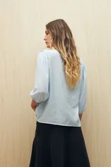 Blusa negra con mangas 3/4 y escote en V con volados.