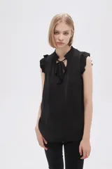Blusa sin mangas color crudo con cuello con lazo y volados en los hombros.