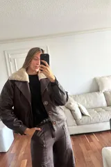 Campera bomber de cuero color vino, con cuello de piel sintética desmontable y corte oversized.