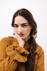 Sweater color mostaza en tejido acanalado, con cuello alto y volados en el escote y los puños.
