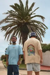 Remera blanca de manga corta con cuello redondo y estampado de tres hongos rojos y la palabra "Tuya" en el frente.