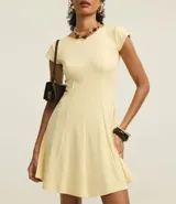 Vestido negro de punto Roma, corto, con escote redondo y mangas cortas. Presenta recortes en el talle que definen la silueta ajustada en el torso y falda acampanada.