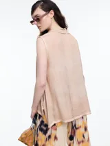 Camisa gris sin mangas confeccionada en viscosa teñida en frío, con efecto gastado. Tiene cuello clásico, cartera oculta y ruedo irregular más largo en los laterales.