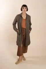 Camisa larga color crema con rayas verticales finas en gris, con botones dorados y bolsillo plaque en la delantera.