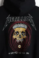 Canguro negro de corte holgado con capucha forrada, bolsillo tipo canguro y estampa frontal del logo de la banda Metallica en color blanco.