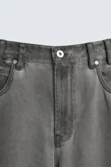 Pantalón de jean gris de corte amplio, estilo balloon fit, con cinco bolsillos, cierre frontal con cremallera y botón, y efecto de color lavado en toda la prenda.