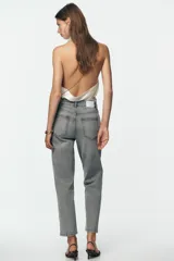 Pantalón de jean azul de tiro alto, corte mom fit, tobillero y con cinco bolsillos. Cierre frontal con cremallera y botón.