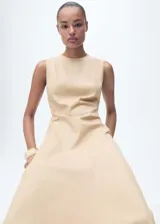 Vestido midi color beige, sin mangas y de corte evasé. Confeccionado en tejido mezcla de algodón y lyocell, con cuello redondo, tirantes anchos y bajo asimétrico deshilachado. Cierre de cremallera en la parte posterior y forro interior.