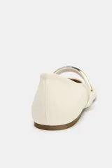 Zapato tipo bailarina color crema con tira sobre el empeine y aplique metálico dorado.