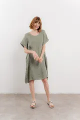 Vestido corto color verde oliva, confeccionado en lino, con corte recto y mangas cortas. Presenta bolsillos laterales y botones decorativos en los laterales.
