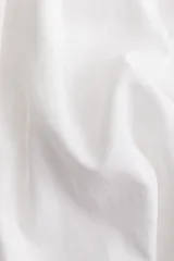 Camisa blanca de lino y viscosa, de corte holgado, con cuello clásico, botones frontales, mangas cortas y bajo redondeado.