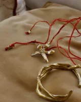 Collar artesanal con dije de flor plateada, realizado con hilo de seda natural teñido a mano.