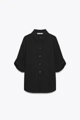 Camisa negra de Zara Woman Collection confeccionada en hilatura con mezcla de viscosa y lyocell. Tiene cuello solapa, manga por debajo del codo ajustable con trabilla y botón, bolsillo de plastrón en el pecho, bajo asimétrico redondeado y cierre frontal con botones.