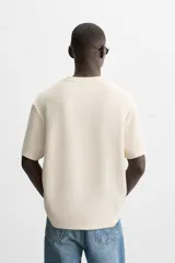 Camiseta de hombre de corte relaxed fit, confeccionada en tejido de algodón compacto con estructura piqué. Presenta cuello redondo y mangas cortas.