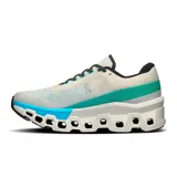 Championes de running On Running Cloudmonster 2, color crema con detalles en turquesa y verde. Presentan el logo de la marca en el lateral y suela con tecnología CloudTec.