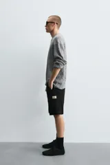 Bermuda cargo de algodón color marrón oscuro, tiro medio, corte regular, con bolsillos laterales de parche con solapa y bolsillos traseros de vivo.