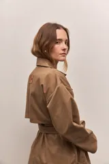 Trench marrón claro de gabardina 100% algodón, con cuello clásico, doble botonadura, mangas largas y corte a la rodilla.