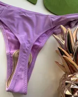 Parte inferior de bikini color lila con tiras ajustables laterales anudadas.