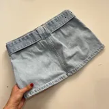 Minifalda de jean celeste con cinturón con hebilla metálica.
