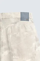 Pantalón de jean blanco, corte holgado y amplio en toda la pierna, tiro medio, tejido ligero, cinco bolsillos, efecto lavado y cierre frontal con cremallera y botón.