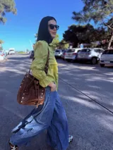 Camisa color verde lima confeccionada en lino, de corte holgado, con cuello camisero, mangas largas abullonadas con puños elásticos y cierre frontal con botones.