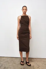 Vestido midi marrón con cuello halter y tirantes finos. Presenta detalle de tejido drapeado y cierre con cremallera oculta en la costura.